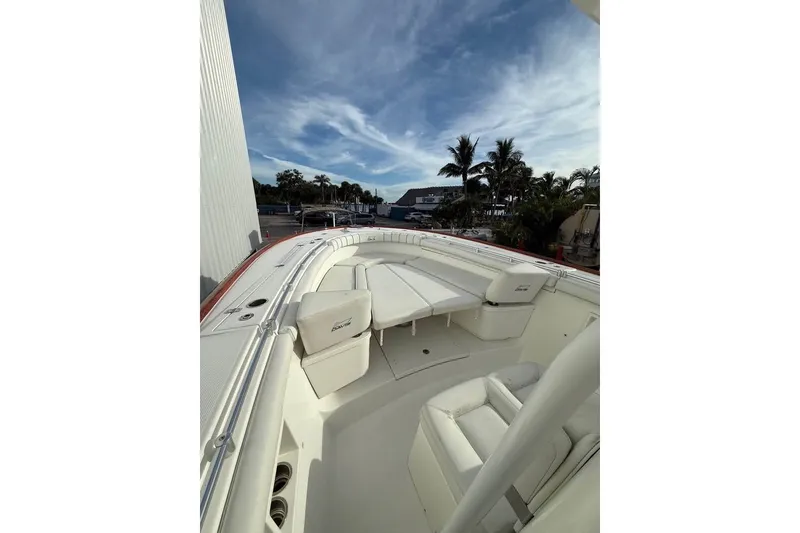 Slide: The Image of 2018 Buddy Davis boat with white seating, docked under a blue sky with palm trees. - 8
