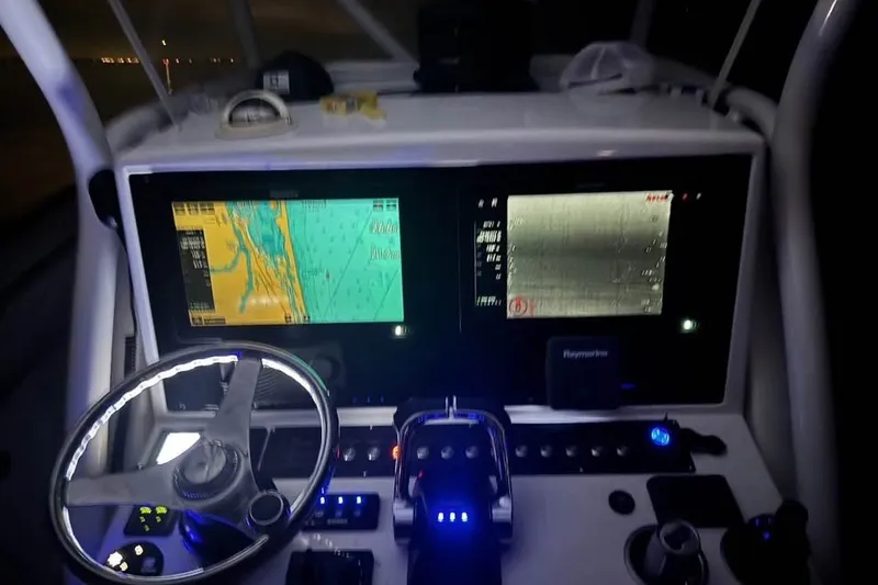 Slide: The Image of Cockpit of a 2018 Buddy Davis boat with illuminated navigation screens and steering wheel. - 3