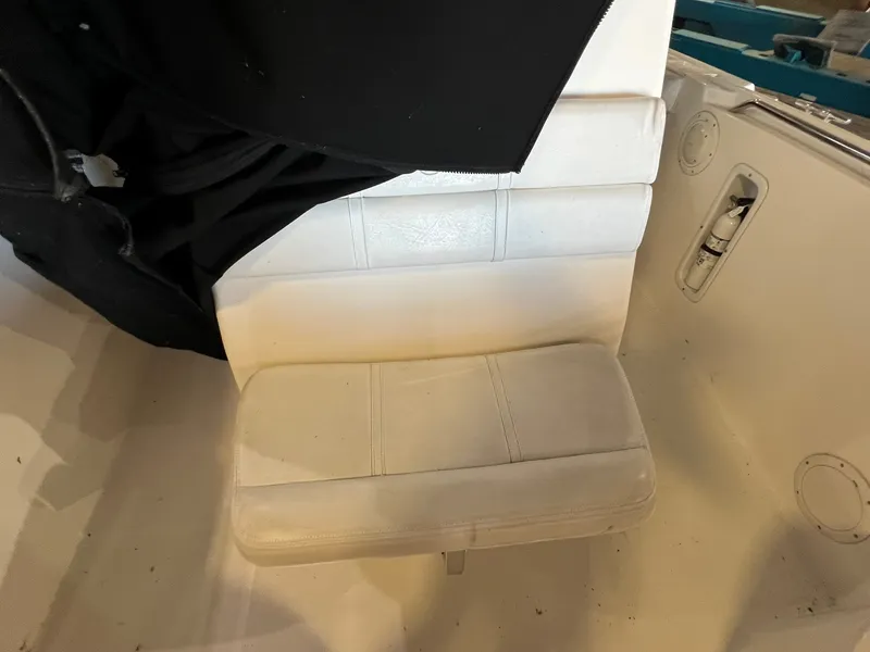 Slide: The Image of A white seat in a boat with black fabric draped over it. A storage compartment is visible nearby. - 7