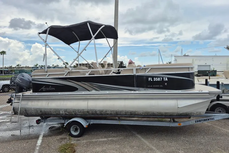 Slide: The Image of 2021 Avalon VLS 2080 QL pontoon boat on trailer, parked outdoors under cloudy sky. - 1