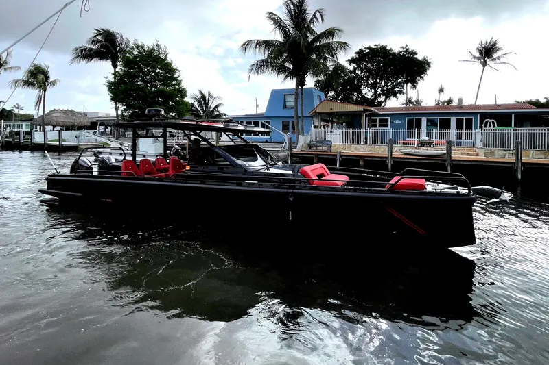 The Image of BRABUS Shadow 900 ST 2023: Luxurious motorboat with black hull and red seats, docked by the shore. - 0