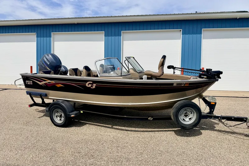 The Image of 2008 G3 Angler V185 FS boat on trailer, parked outside blue building. - 0