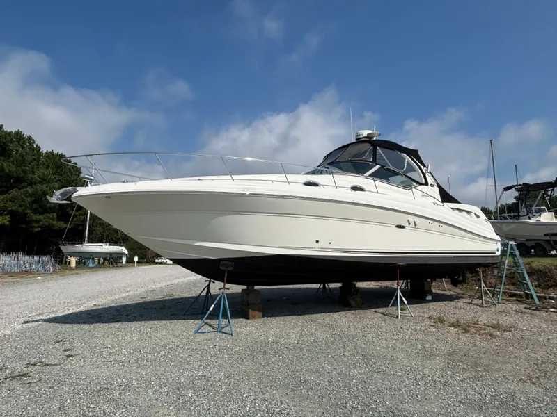 The Image of A 2005 Sea Ray 340 Sundancer is on a gravel lot, supported by stands. - 0