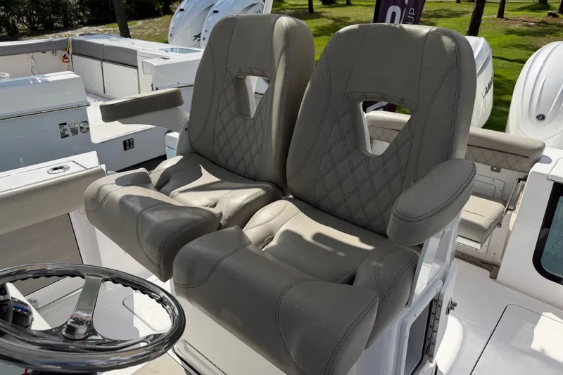 Slide: The Image of Two cushioned captain's chairs with armrests and a steering wheel on a modern boat. - 32