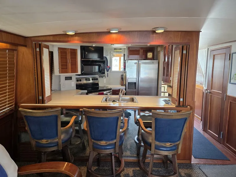Slide: The Image of Interior of a 1976 Chris-Craft Roamer 60 with kitchen and bar stools. - 29