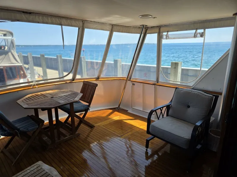Slide: The Image of The 1976 Chris-Craft Roamer 60 features an elegant deck with wooden flooring, table, and chairs. - 33
