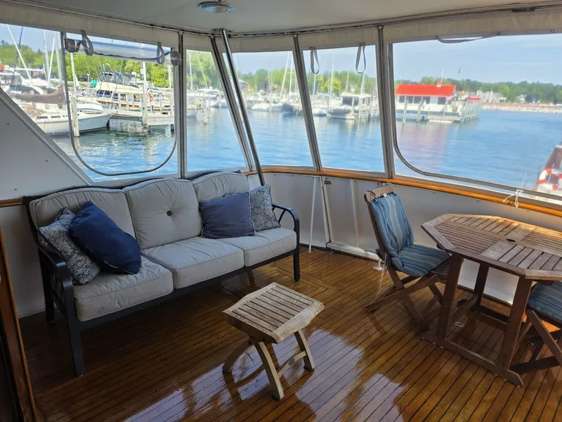 Slide: The Image of A cozy seating area on a boat with wooden flooring, sofa, and table, docked at a marina. - 34