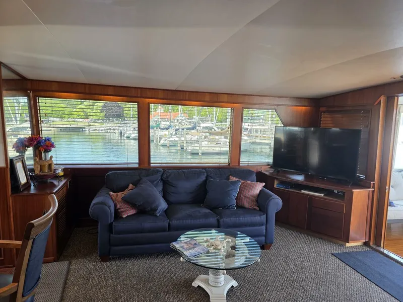 Slide: The Image of Interior of a 1976 Chris-Craft Roamer 60 with a sofa, TV, and marina view. - 30