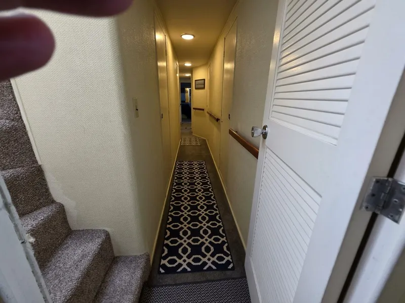 Slide: The Image of A narrow hallway with carpet and stairs inside a boat. - 46