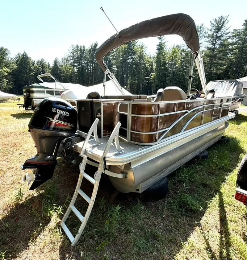 Slide: The Image of A 2023 Bennington 21 SXSAPG pontoon boat with Yamaha outboard motor, parked on grass, surrounded by trees. - 4