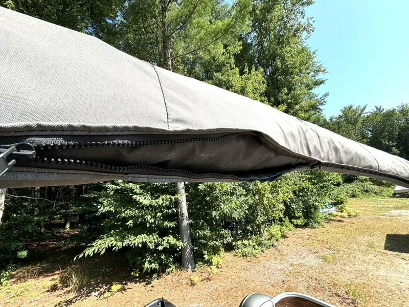 Slide: The Image of A gray Bimini top on a boat, surrounded by trees and blue sky. - 27
