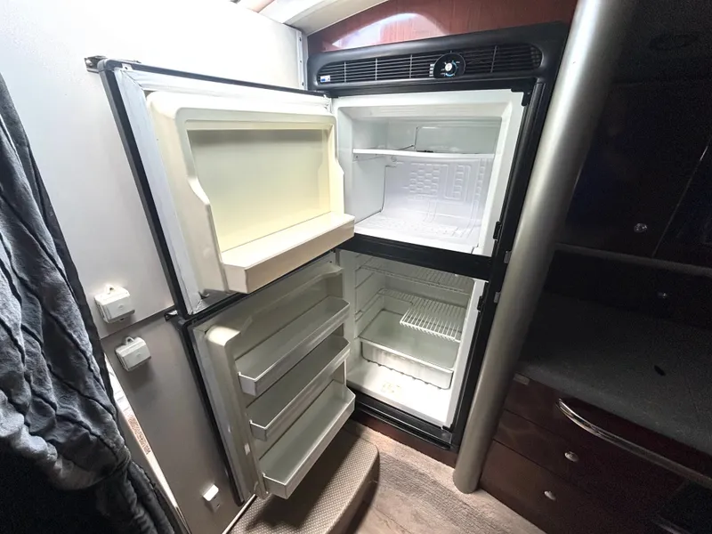 Slide: The Image of An open refrigerator in a boat cabin with multiple shelves and a freezer compartment. - 37