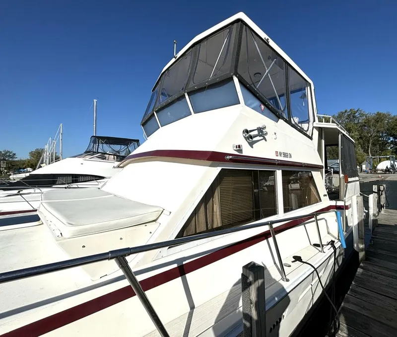 Slide: The Image of A 1987 white motor yacht with a red stripe, docked on a sunny day. - 6