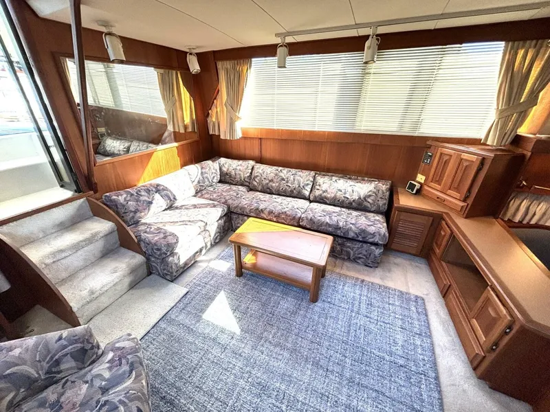 Slide: The Image of The interior of a 1987 Viking Motor Yacht with a large patterned sofa and wooden furnishings. - 43
