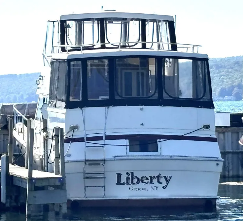 Slide: The Image of 1987 Viking Motor Yacht docked in a serene harbor with wooded hills in the background. - 8