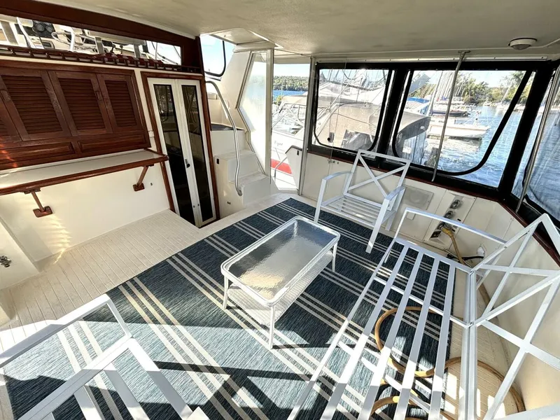 Slide: The Image of Interior of a 1987 Viking Motor Yacht with white furniture and large windows overlooking the marina. - 20