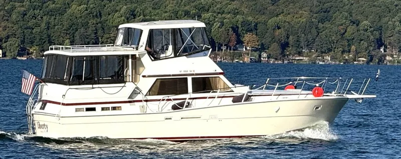 Slide: The Image of A 1987 white motor yacht cruising on a lake, surrounded by wooded shores. - 5