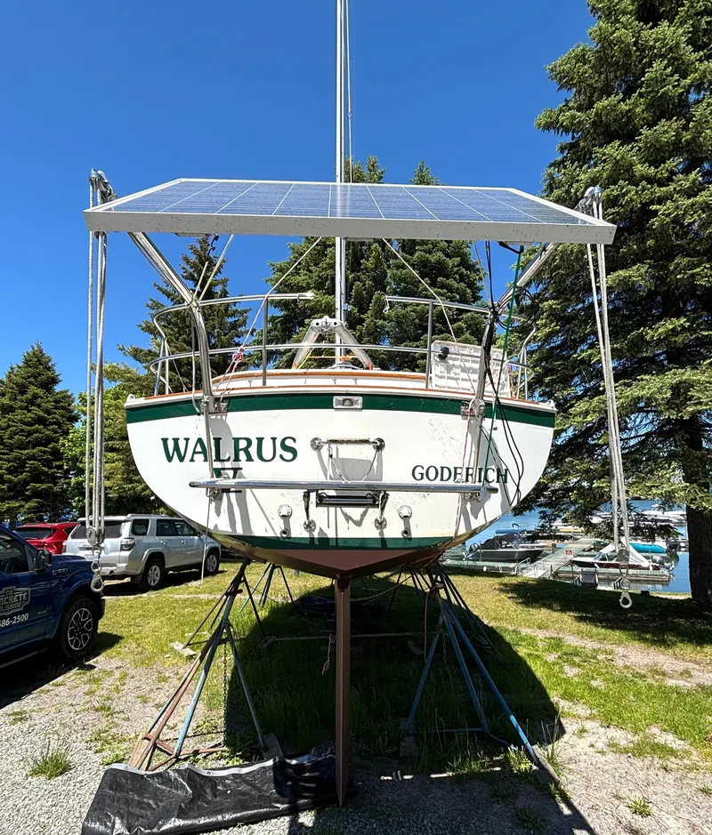 Slide: The Image of A 1985 Nonsuch 30 Ultra sailboat on a stand, surrounded by trees and cars. - 7