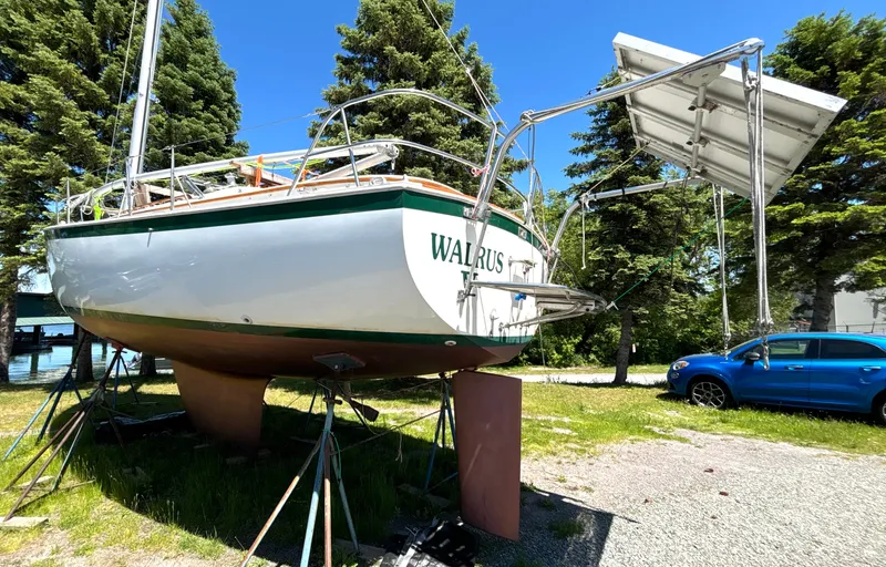 Slide: The Image of A 1985 Nonsuch 30 Ultra sailboat on land, surrounded by trees and a car. - 8