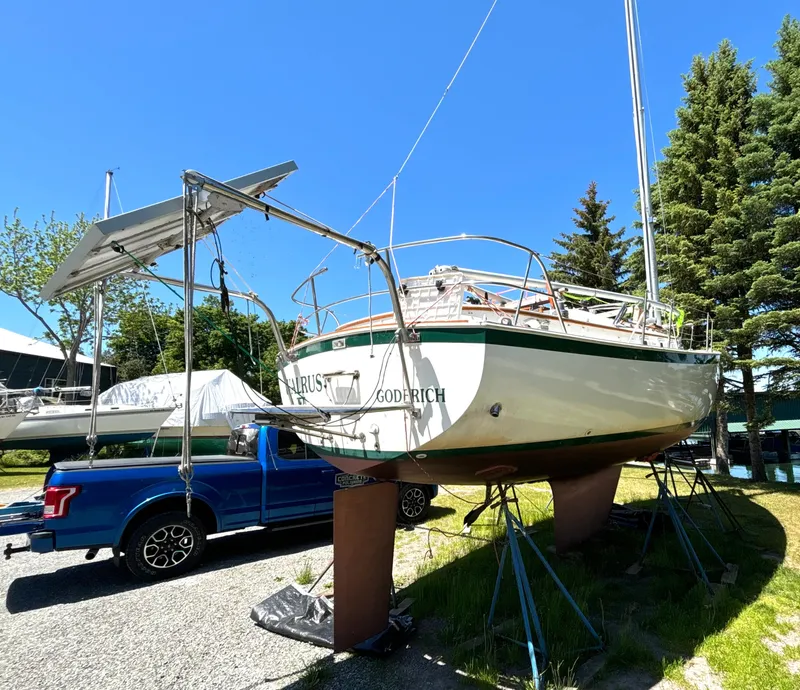 Slide: The Image of A 1985 Nonsuch 30 Ultra on a stand next to a blue truck, surrounded by trees. - 6