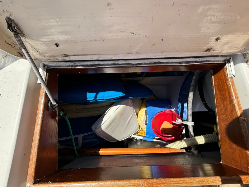 Slide: The Image of A storage compartment on a 1985 Nonsuch 30 Ultra, filled with various items and hoses. - 29