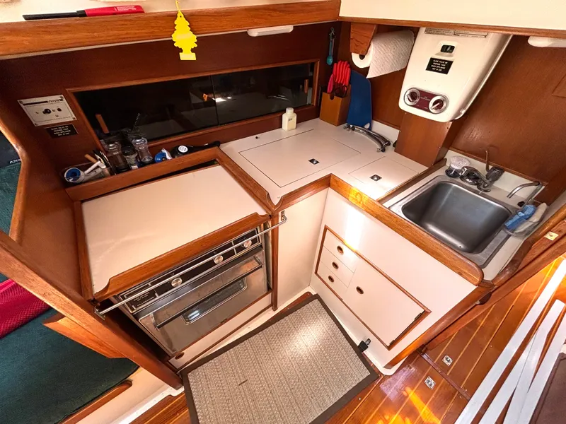 Slide: The Image of The galley of a 1985 Nonsuch 30 Ultra with a sink, stove, and wood paneling. - 35