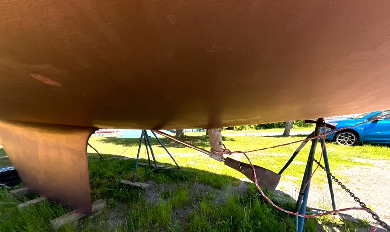 Slide: The Image of The hull of a 1985 Nonsuch 30 Ultra is supported by stands outdoors. - 13