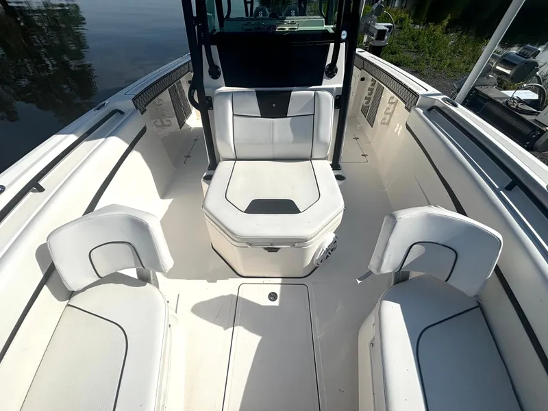Slide: The Image of The image shows the cockpit of a 2019 Wellcraft 302 Center Console boat with white seating. - 35