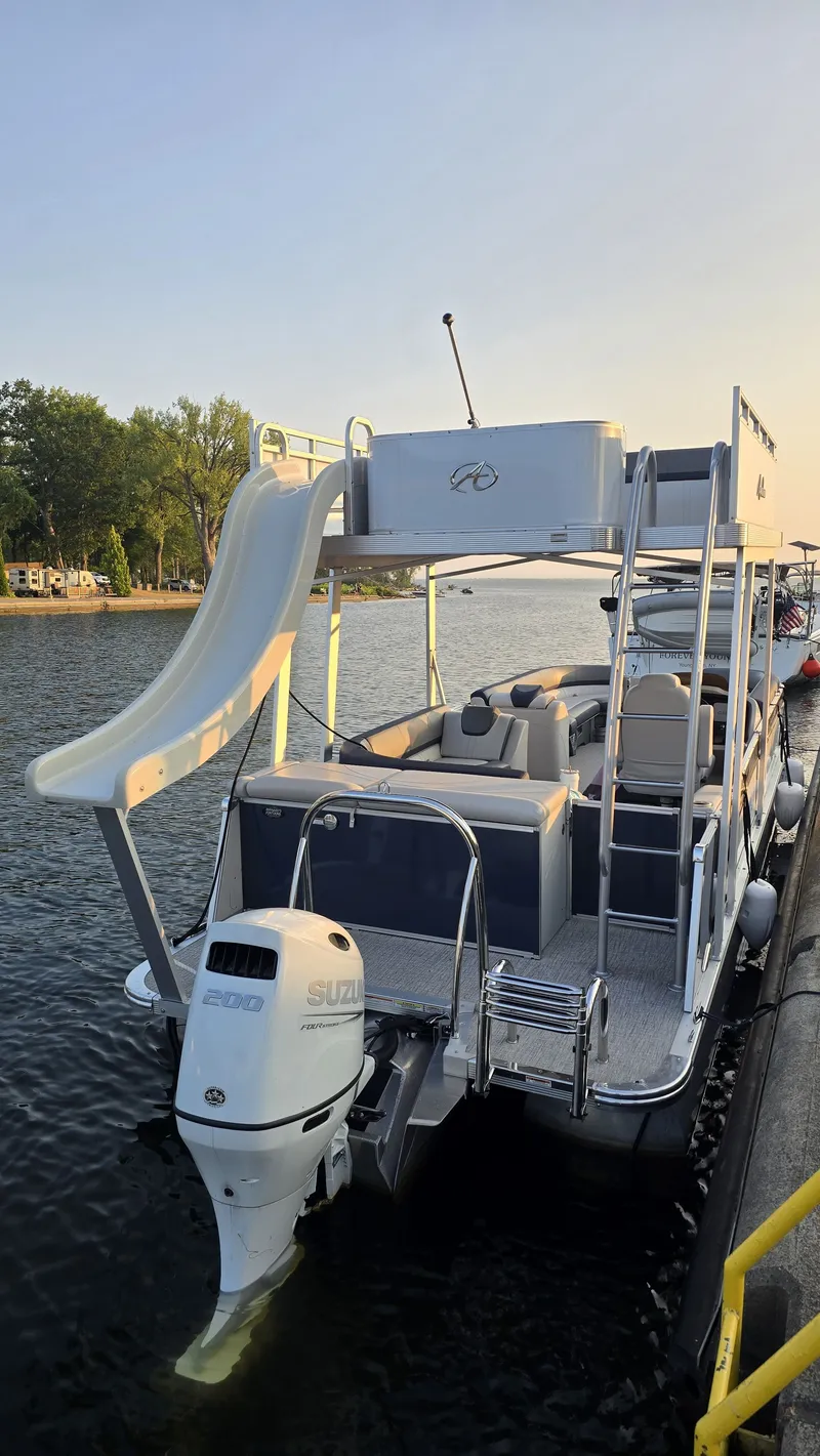 Slide: The Image of 2023 Avalon Catalina 2585 CRFS Funship with a waterslide and outboard motor at the dock. - 3