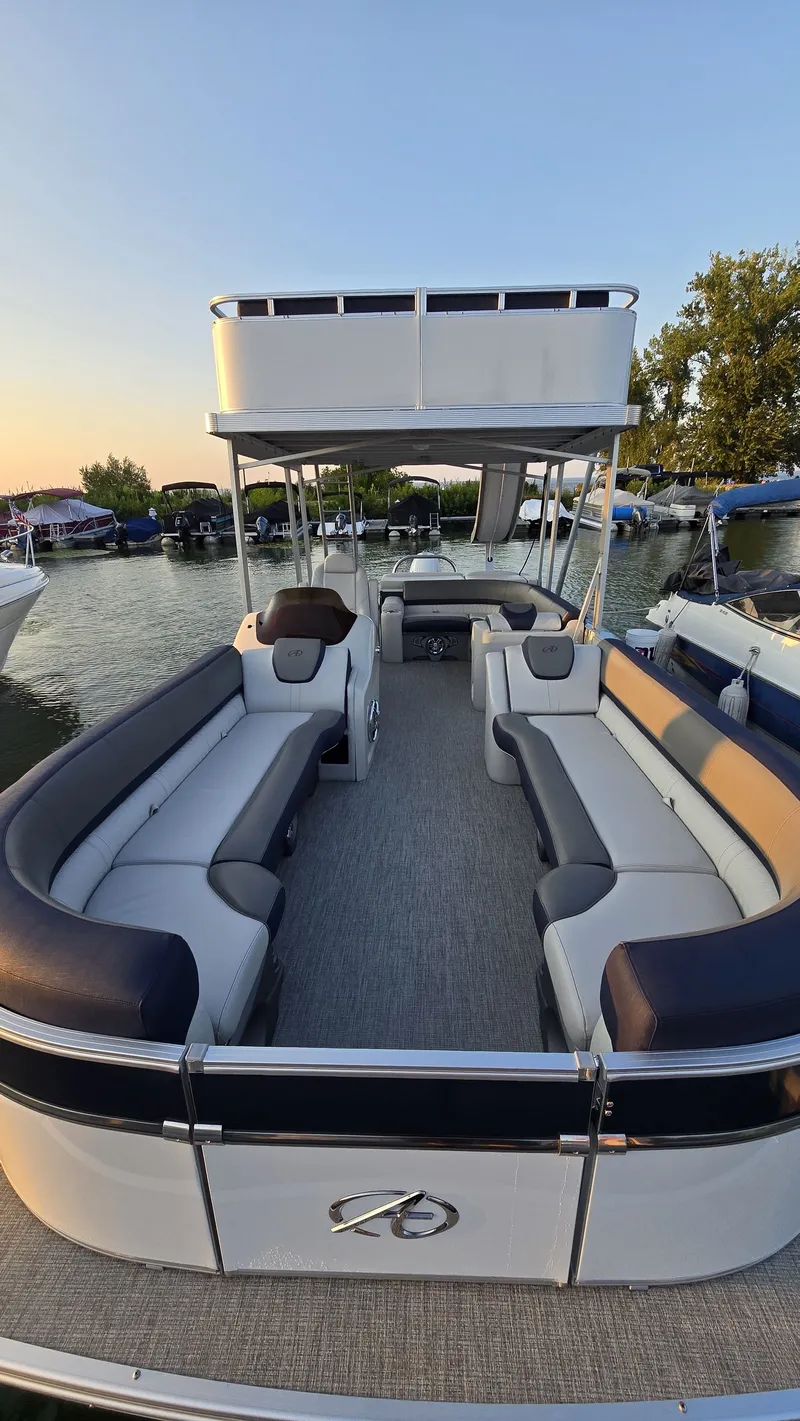 Slide: The Image of The image shows a two-level pontoon boat with gray and blue seating, situated on calm water. - 5