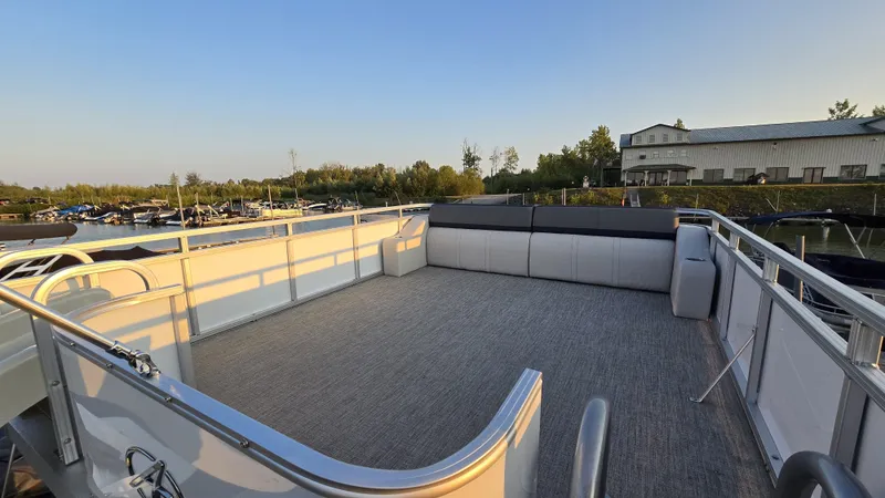 Slide: The Image of The image shows the spacious upper deck of a 2023 Avalon Catalina 2585 CRFS Funship, overlooking a calm marina. - 21