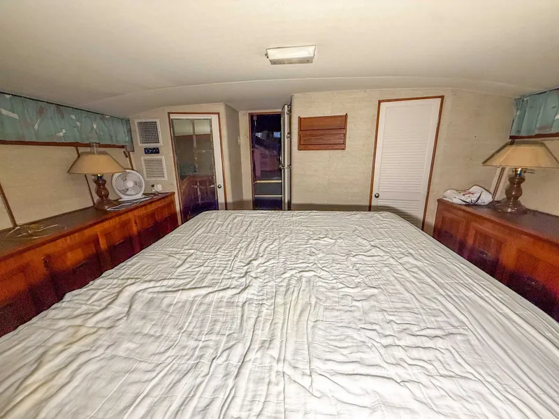 Slide: The Image of The image shows the bedroom of a 1977 Pacemaker FB Motor Yacht with a large bed and wooden furniture. - 40