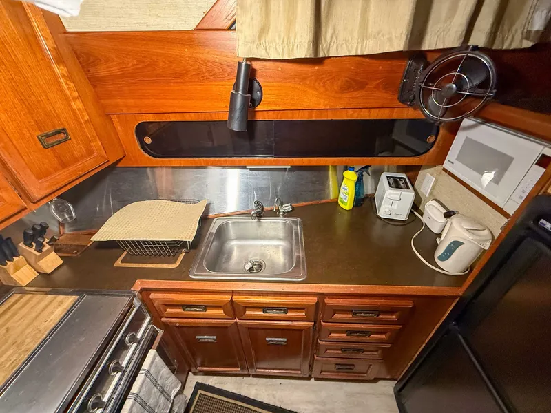 Slide: The Image of The kitchen of a 1977 Pacemaker FB Motor Yacht with wooden cabinets, sink, and appliances. - 30