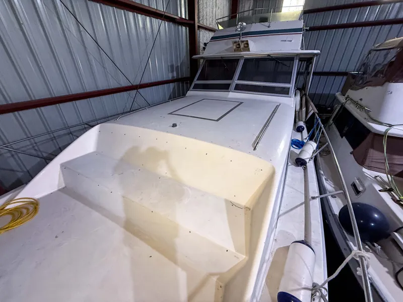 Slide: The Image of A 1977 Pacemaker FB Motor Yacht in a warehouse, featuring a spacious deck and windows. - 19
