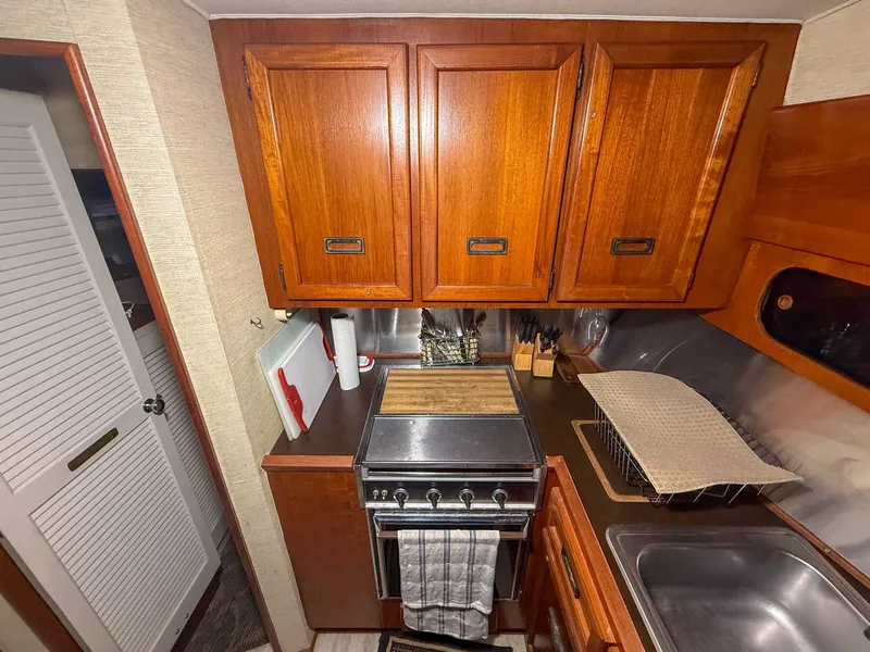 Slide: The Image of The galley of a 1977 Pacemaker FB Motor Yacht with wooden cabinets, stove, and sink. - 29
