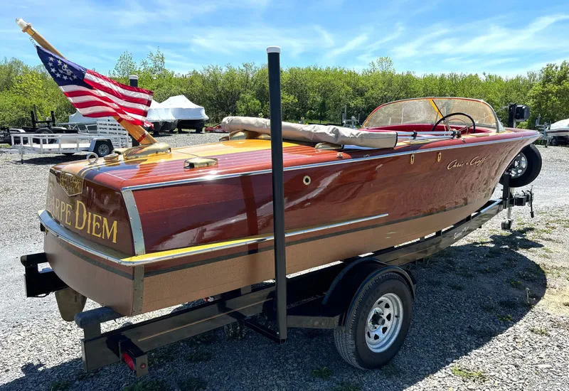 Slide: The Image of A classic 1956 Chris-Craft Capri boat with wooden finish and an American flag. - 3