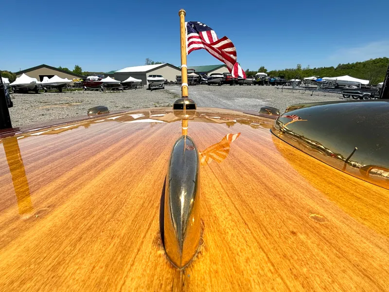 Slide: The Image of A shiny wooden deck of a 1956 Chris-Craft Capri with an American flag in the background. - 12