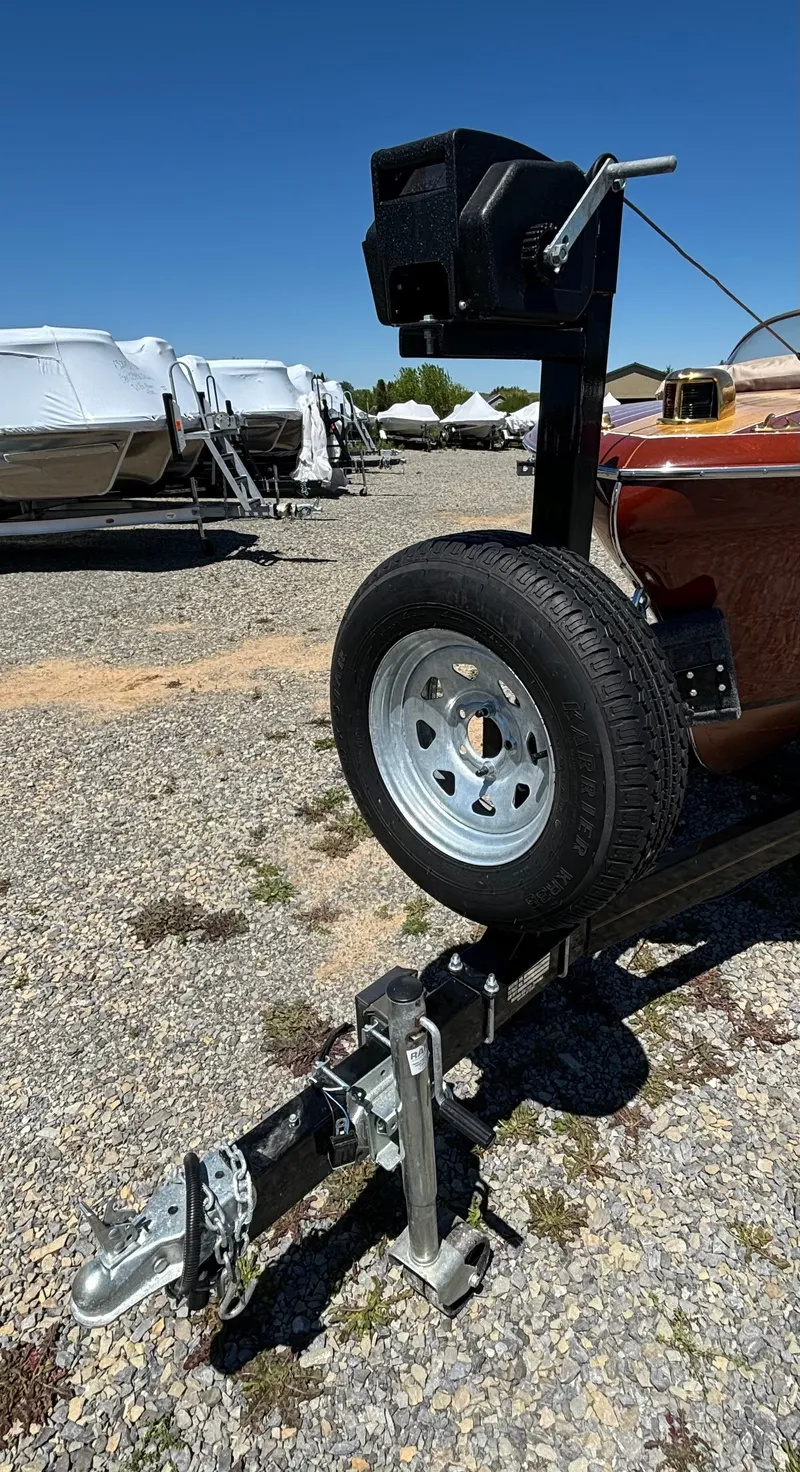Slide: The Image of A 1956 Chris-Craft Capri on a trailer, surrounded by other boats on a gravel lot. - 33