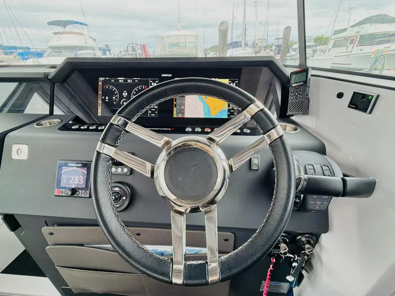Slide: The Image of The image shows the helm of a 2020 Axopar 37 XC Cross Cabin boat in a marina. - 33