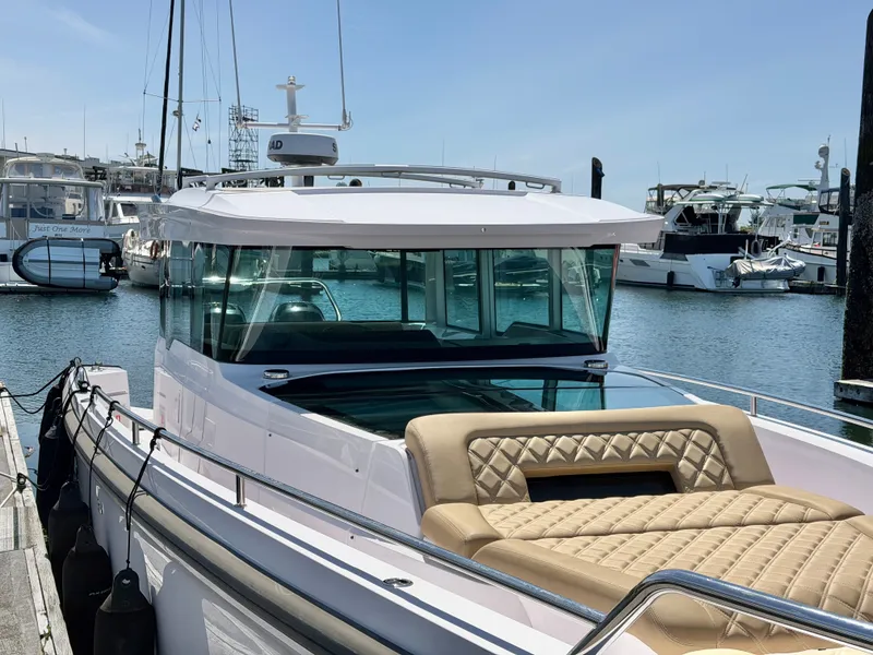 Slide: The Image of A 2020 Axopar 37 XC Cross Cabin docked in a marina. It features a modern design with beige seating. - 18