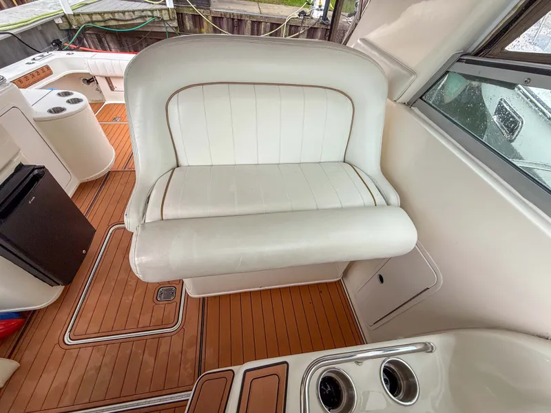 Slide: The Image of The 1997 Sea Ray 330 Express Cruiser features a white bench seat and sleek wood deck. - 16