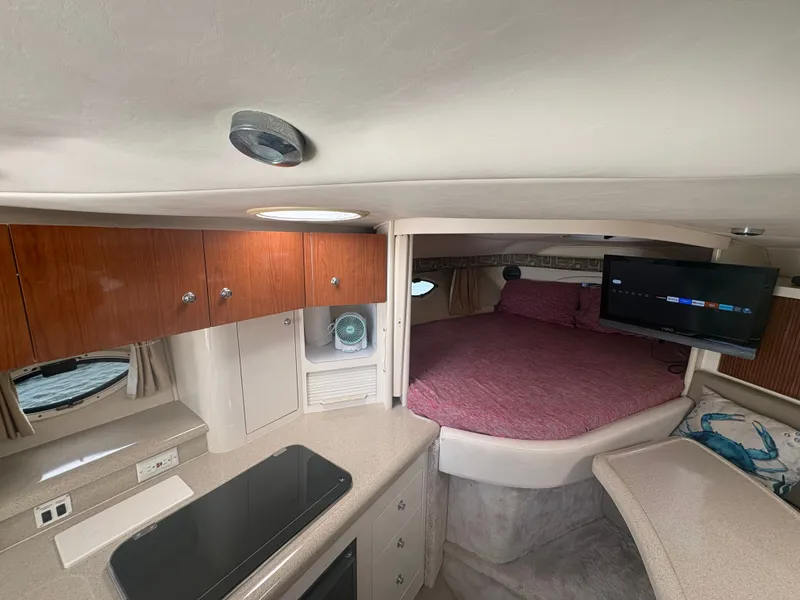 Slide: The Image of Interior of a 2000 Monterey 322 Cruiser with a kitchen, sleeping area, and TV. - 26
