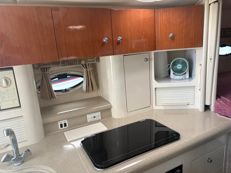 Slide: The Image of The galley of a 2000 Monterey 322 Cruiser with wooden cabinets and a cooktop. - 24