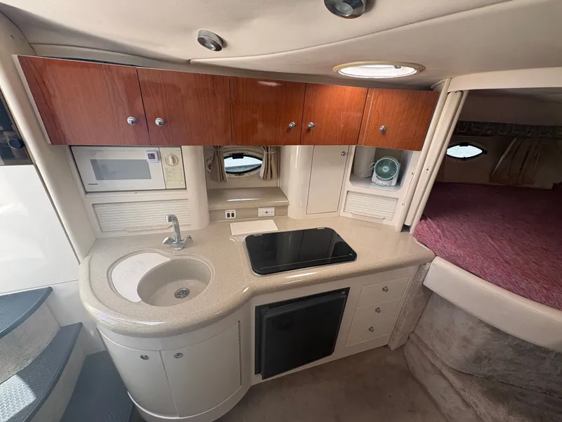 Slide: The Image of The interior of a 2000 Monterey 322 Cruiser features a compact kitchen with a sink, stove, and fridge. - 25