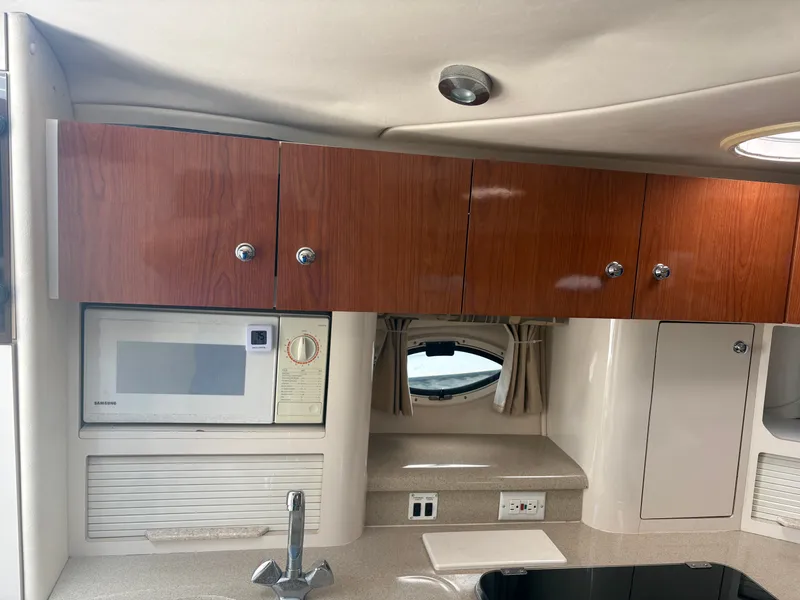 Slide: The Image of The interior of a 2000 Monterey 322 Cruiser features a kitchen with a microwave and wooden cabinets. - 23