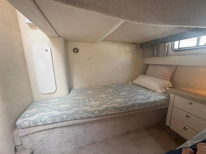 Slide: The Image of The cabin of the 2000 Monterey 322 Cruiser features a single bed with patterned bedding and a pillow. - 40
