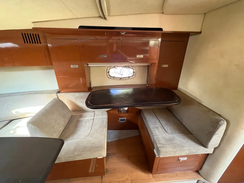 Slide: The Image of Interior of the 2010 Sea Ray Sundancer 310 with a cozy seating area and wooden table. - 23