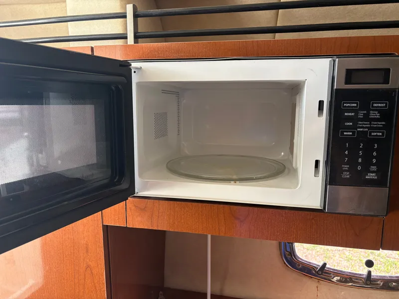 Slide: The Image of A microwave in a boat cabin with wooden cabinetry and a small window. - 30