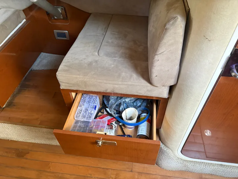 Slide: The Image of An open storage compartment under a seat in a 2010 Sea Ray Sundancer 310 reveals tools and accessories. - 45