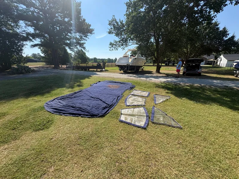Slide: The Image of A 2010 Sea Ray Sundancer 310 on a trailer. Covers and window panels are laid out on the grass. - 41
